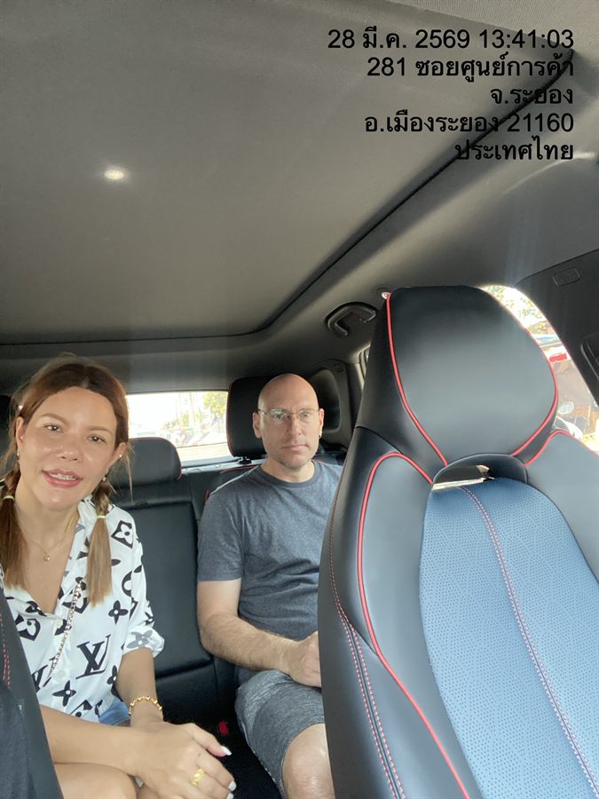 A couple riding in the back of a WayGo sedan in Mueang Rayong.