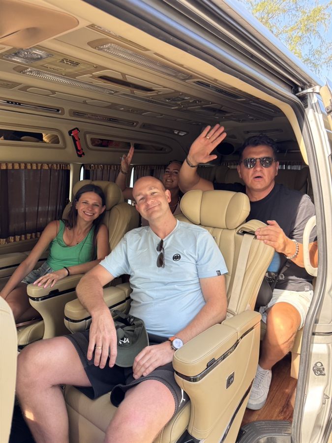 A group of four waving from the leather seats of a WayGo VIP van.